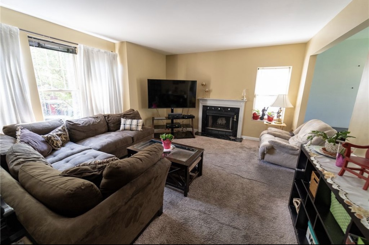 Before: the living room with yellow walls, carpet, and crowded furniture